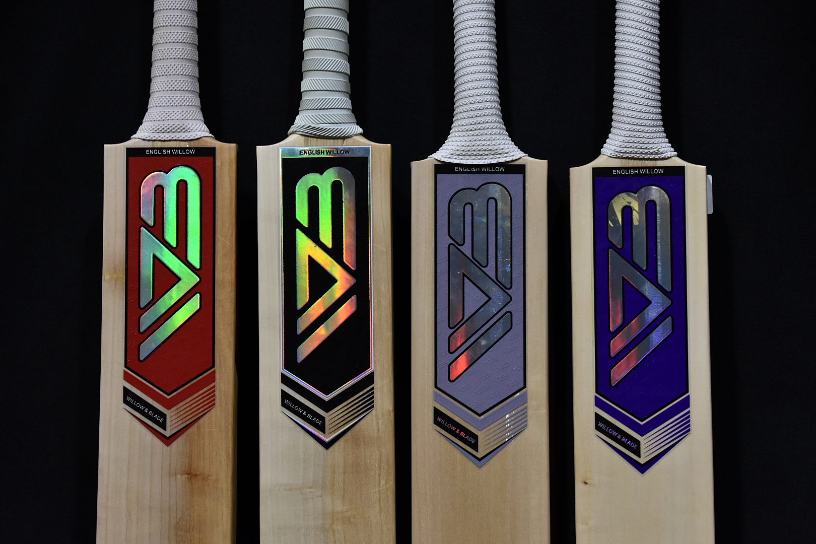 Four Willow & Blade bats with red, black, grey and purple stickers